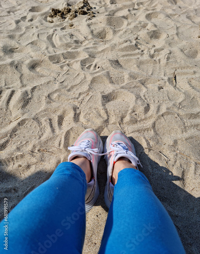 Sneakers on the sandy beach are your legs