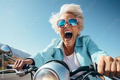 An elderly cheerful woman with gray hair rides a blue scooter and smiles. Generated by AI. © index74