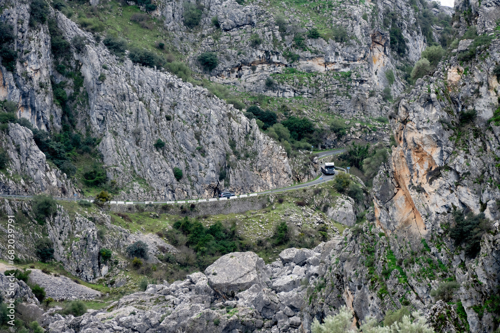 A large truck and SUV approaching each other on a narrow winding road on MA-8403 in Andalucia, Spain