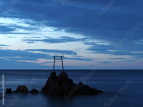 夕焼けの空と岩の上に建造された鳥居