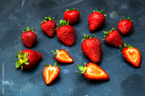Fresh red strawberries, scattered organic strawberries on a black background, close-up.
