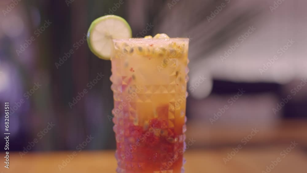 Yellow-pink cocktail with passion fruit and strawberries in a glass. A glass with ice and a slice of lime on the table. A cocktail in a glass stands on a table in a restaurant or bar. Yellow-pink cocktail with passion fruit and strawberries in a glass. A glass with ice and a slice of lime on the table. A cocktail in a glass stands on a table in a restaurant or bar.