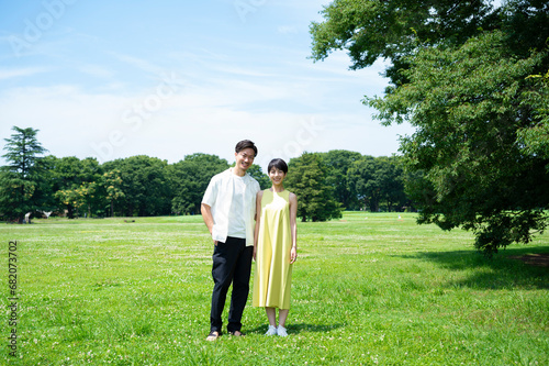 A beautiful Asian couple holding hands and smiling happily in a beautiful green park.  © Monet