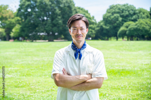 Portrait of a young Asian man with glasses smiling on a sunny day in a park with lush green grass. Healthy living, taking care of body and mind, urban living, autonomy, happy lifestyle

