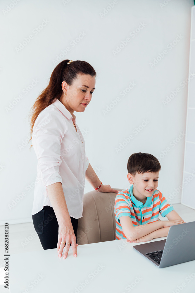 Mom helps her son do school assignment on the computer