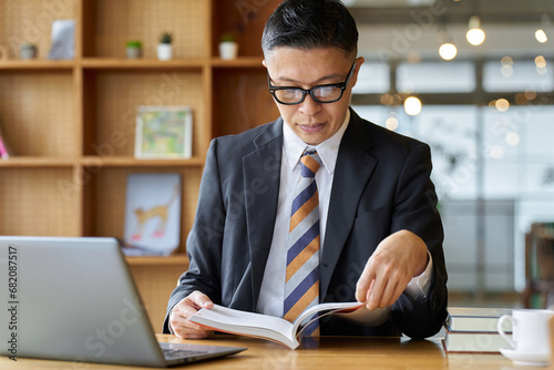 勉強のためカフェで読書をするアジア人ビジネスマン