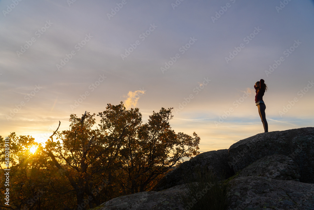 Woman putting her hair in a ponytail at sunrise on top of a mountain