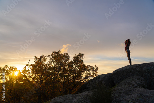 Woman putting her hair in a ponytail at sunrise on top of a mountain