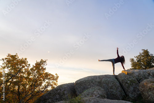Woman practicing yoga at sunrise in nature