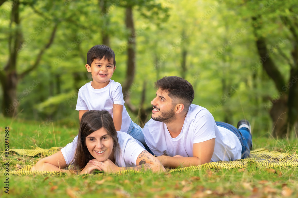 Boy piggybacking his mother lying outdoors with his parents Boy piggybacking his mother lying outdoors with his parents