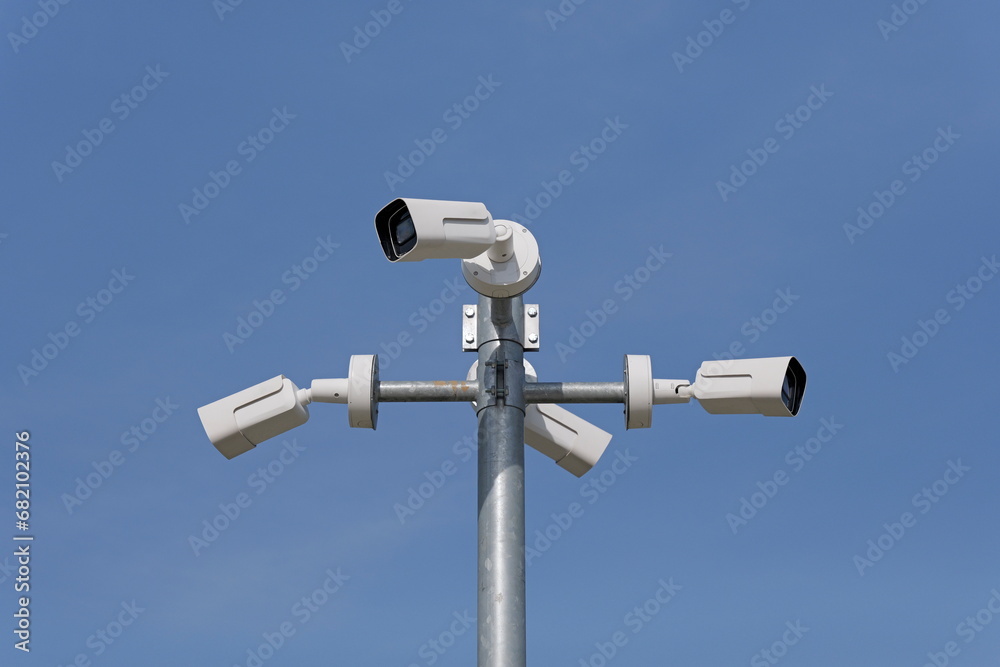 Pole mounted security cameras against blue sky Pole mounted security cameras against blue sky