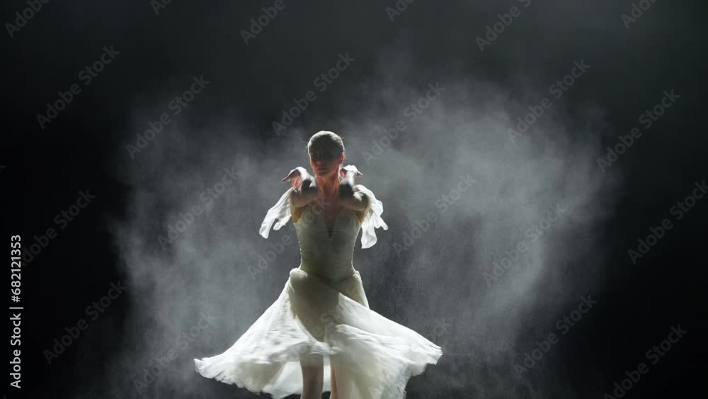 Dramatic dance, elegant woman in a white tutu, ballerina dance and perform choreographic elements on a black background, using magnesia, haze effect on a dark stage. Dramatic dance, elegant woman in a white tutu, ballerina dance and perform choreographic elements on a black background, using magnesia, haze effect on a dark stage.