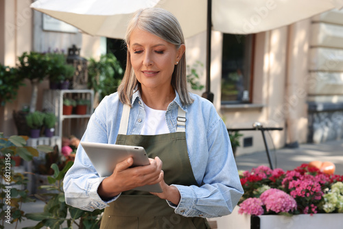 Business owner using tablet near her flower shop outdoors