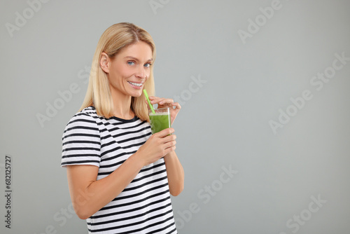 Happy woman with glass of fresh celery juice on light grey background. Space for text