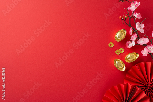 Immerse yourself in Chinese New Year ambiance through this top-view arrangement featuring fans, Feng Shui items, symbolic coins, sycee and sakura blooms on red setting, ready for text or advertising © ActionGP