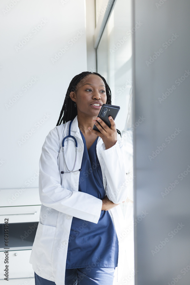 African american female doctor wearing lab coat talking on smartphone in hospital African american female doctor wearing lab coat talking on smartphone in hospital
