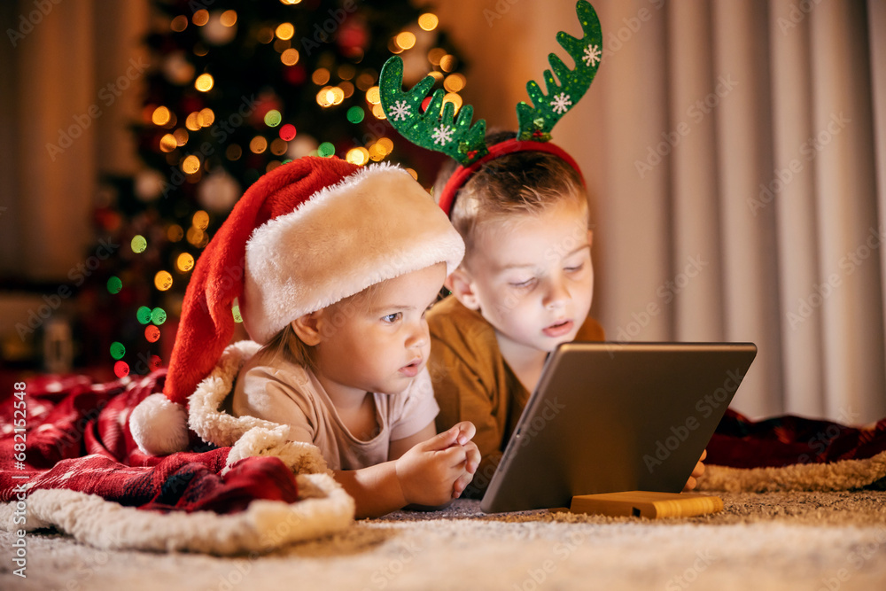 Focused children looking at tablet on christmas and new year's eve at home. Focused children looking at tablet on christmas and new year's eve at home.