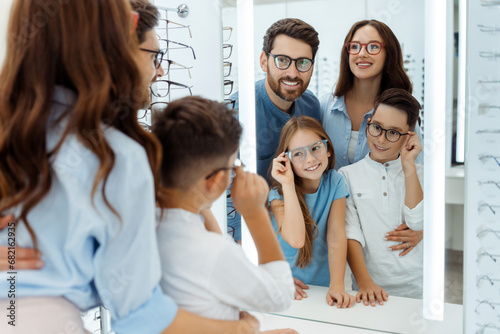 Happy parents and kids looking at mirror in optical store photo
