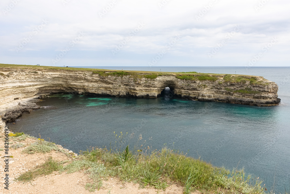 Cape Tarkhankut on the Crimean peninsula. The rocky coast of the Dzhangul Reserve in the Crimea. The Black Sea. Turquoise sea water. Rocks and grottoes of Cape Tarkhankut.