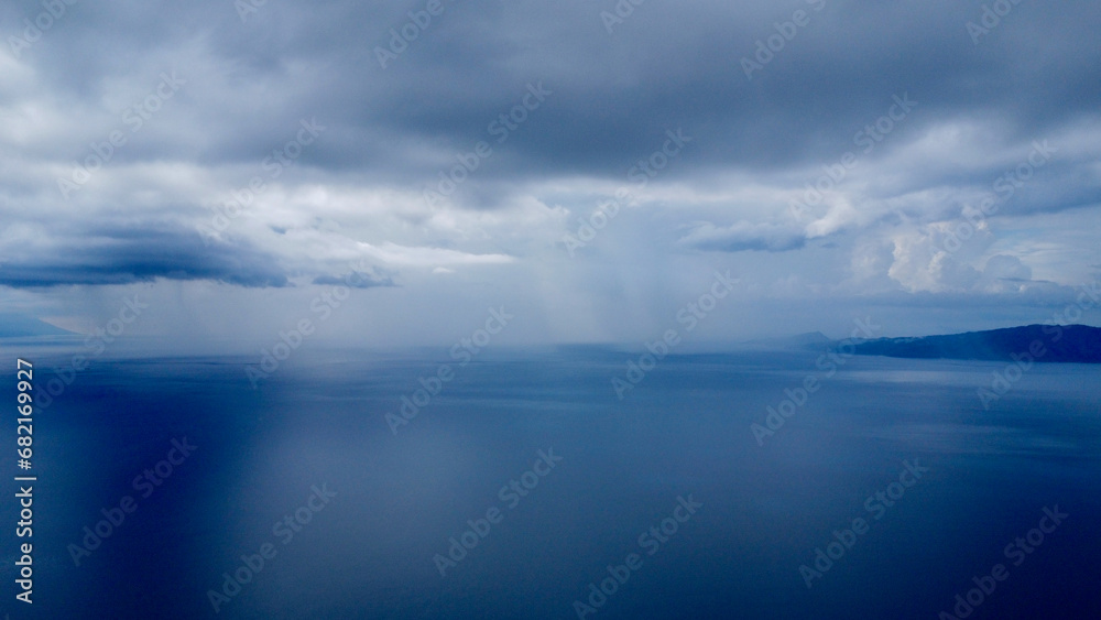 Thunderclouds and rain over the sea. Aerial view of rain over the sea on the horizon.