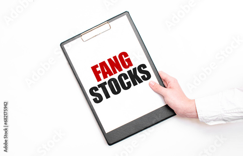 A businessman holds a folder with paper sheet with the text FANG STOCKS. Business concept.