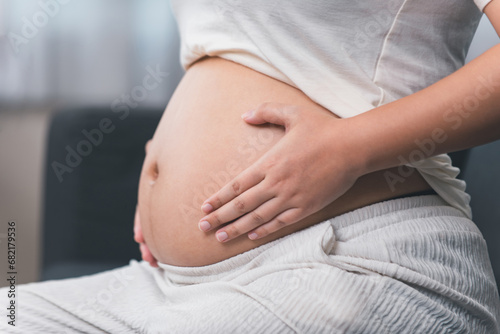 Young pregnant woman touching her belly and caring about her health, Young woman expecting a baby..