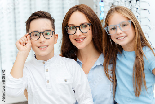 Happy woman and kids wearing glasses in optics