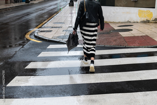 Woman in black and white striped skirt at a pedestrian crossing