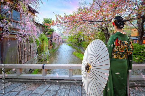 Young Japanese woman in traditional Kimono dress strolls on Tatsumi bashi bridge  over Shirakawa river in Gion district, Kyoto, Japan