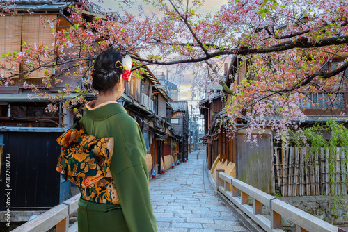 Young Japanese woman in traditional Kimono dress strolls on Tatsumi bashi bridge  over Shirakawa river in Gion district, Kyoto, Japan photo