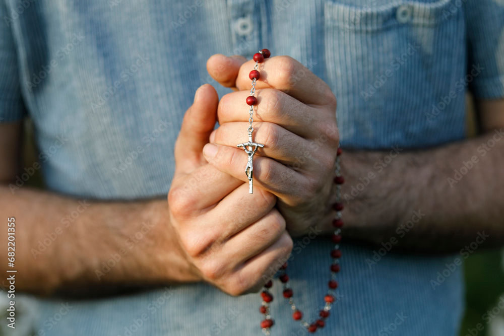 Young man praying with rosary in Eure, France. - obrazy, fototapety, plakaty 