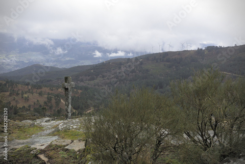 Stone cross on rock with wind turbines behind - Perched on a rock, a stone cross shares the landscape with towering wind turbines, shot with the Sony RX100. photo