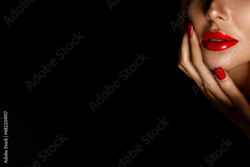 фотографія Beautiful woman in elegant makeup with red lips and nails posing sensually on a black background