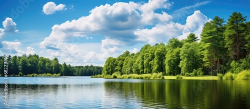 During my summer vacation, I visited a beautiful park nestled forest, where I was surrounded by the stunning landscape of blue skies, fluffy white clouds, and a serene lake reflecting the lush