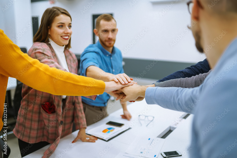 A group of people in an office meeting collectively resolve an issue by raising their hands. Colleagues in the office sign an agreement, hands forward. Concept of business, negotiations. A group of people in an office meeting collectively resolve an issue by raising their hands. Colleagues in the office sign an agreement, hands forward. Concept of business, negotiations.