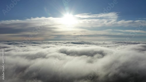 Slow aerial flight toward bright, behind cloud sun above heaven like cloud top photo