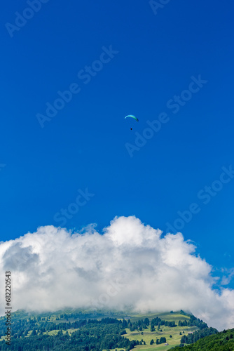 Solo paragliding in the clear blue sky over the mountains, Swiss Alps in Switzerland
