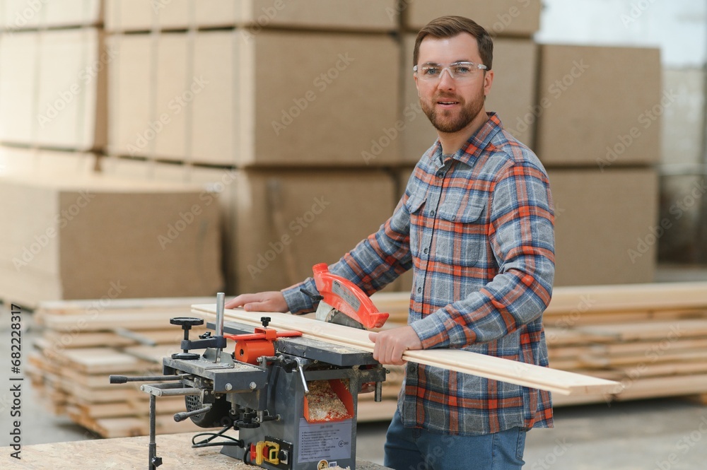 A carpenter works on woodworking the machine tool. Man collects furniture boxes. Saws furniture details with a circular saw. Process of sawing parts in parts. Against the background of the workshop. A carpenter works on woodworking the machine tool. Man collects furniture boxes. Saws furniture details with a circular saw. Process of sawing parts in parts. Against the background of the workshop.