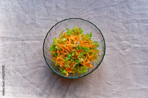 Salad prepared with curly lettuce, carrots, olive oil and lemon is ready to eat in a bowl