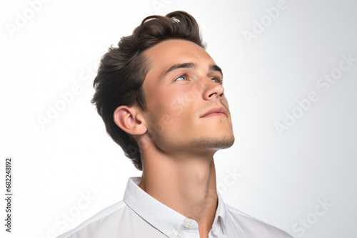 Man wearing white shirt and looking upwards. Curiosity, optimism, or inspiration. It can be used in various contexts such as business, education, or lifestyle