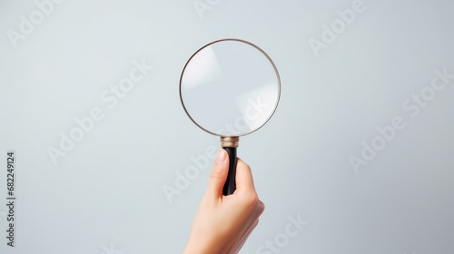 Hand holding magnifying glass on isolated light grey background with AI