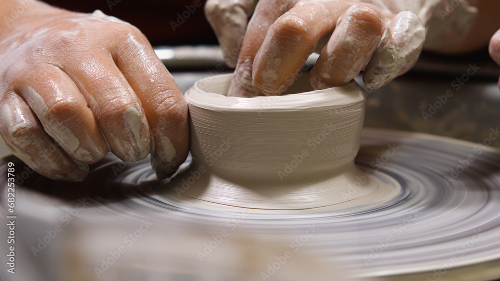 Potter's hands creating a cup of clay on a potter's wheel. Work in the pottery workshop close-up. The concept of handwork, art and craft.