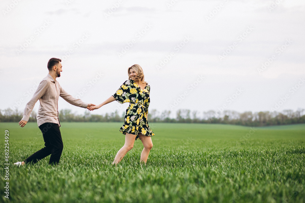 Young couple in the field with green grass