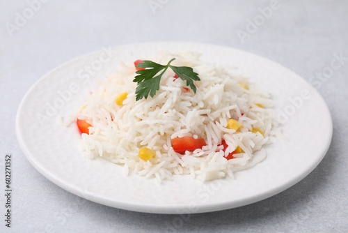 Delicious rice with vegetables and parsley on light gray table, closeup