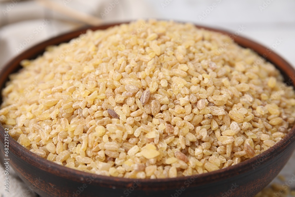 Raw bulgur in bowl on table, closeup Raw bulgur in bowl on table, closeup