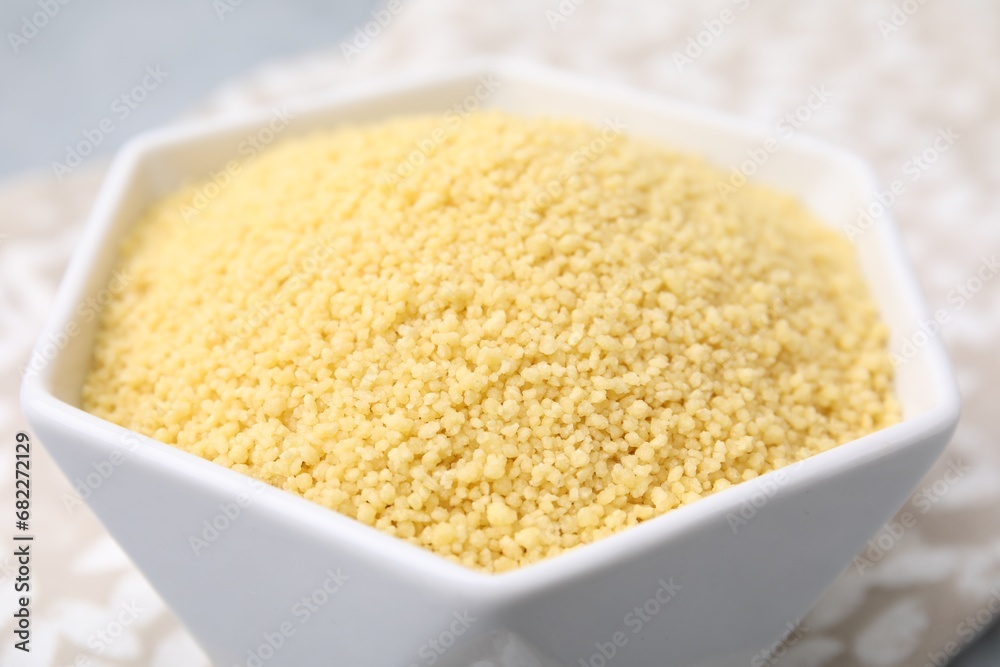 Raw couscous in bowl on table, closeup Raw couscous in bowl on table, closeup