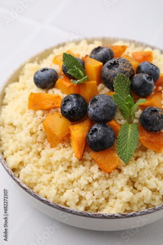 Bowl of tasty couscous with blueberries, pumpkin and mint on table, closeup