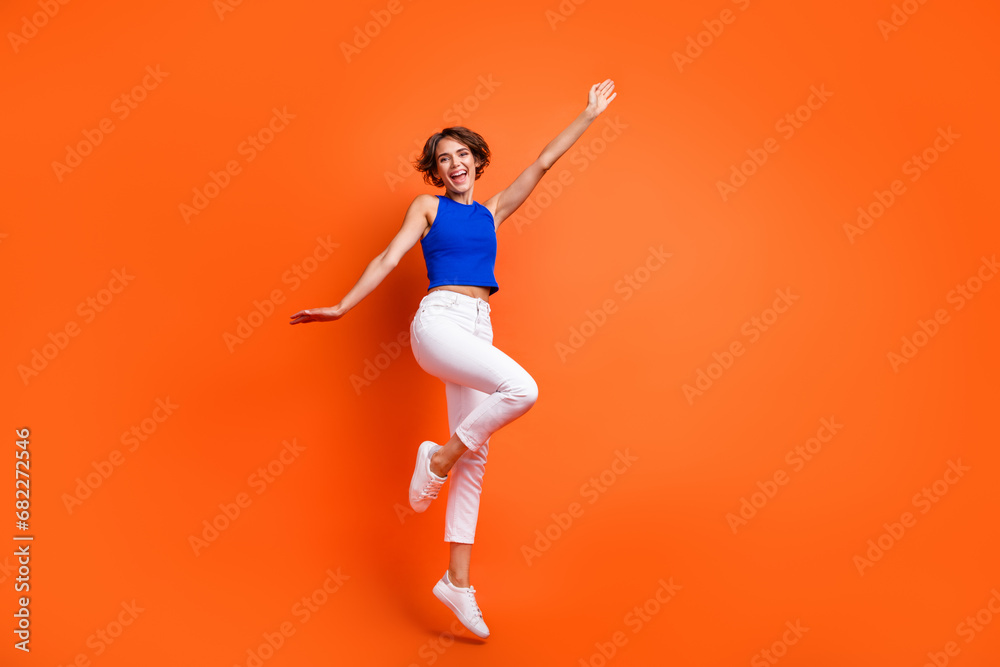 Full size photo of active overjoyed girl jumping have good mood empty space isolated on orange color background - obrazy, fototapety, plakaty 