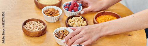 cropped view of woman arranging bowls with various and wholesome plant-based food on table, banner