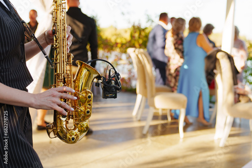 A woman musician plays the saxophone at an open-air party.  photo
